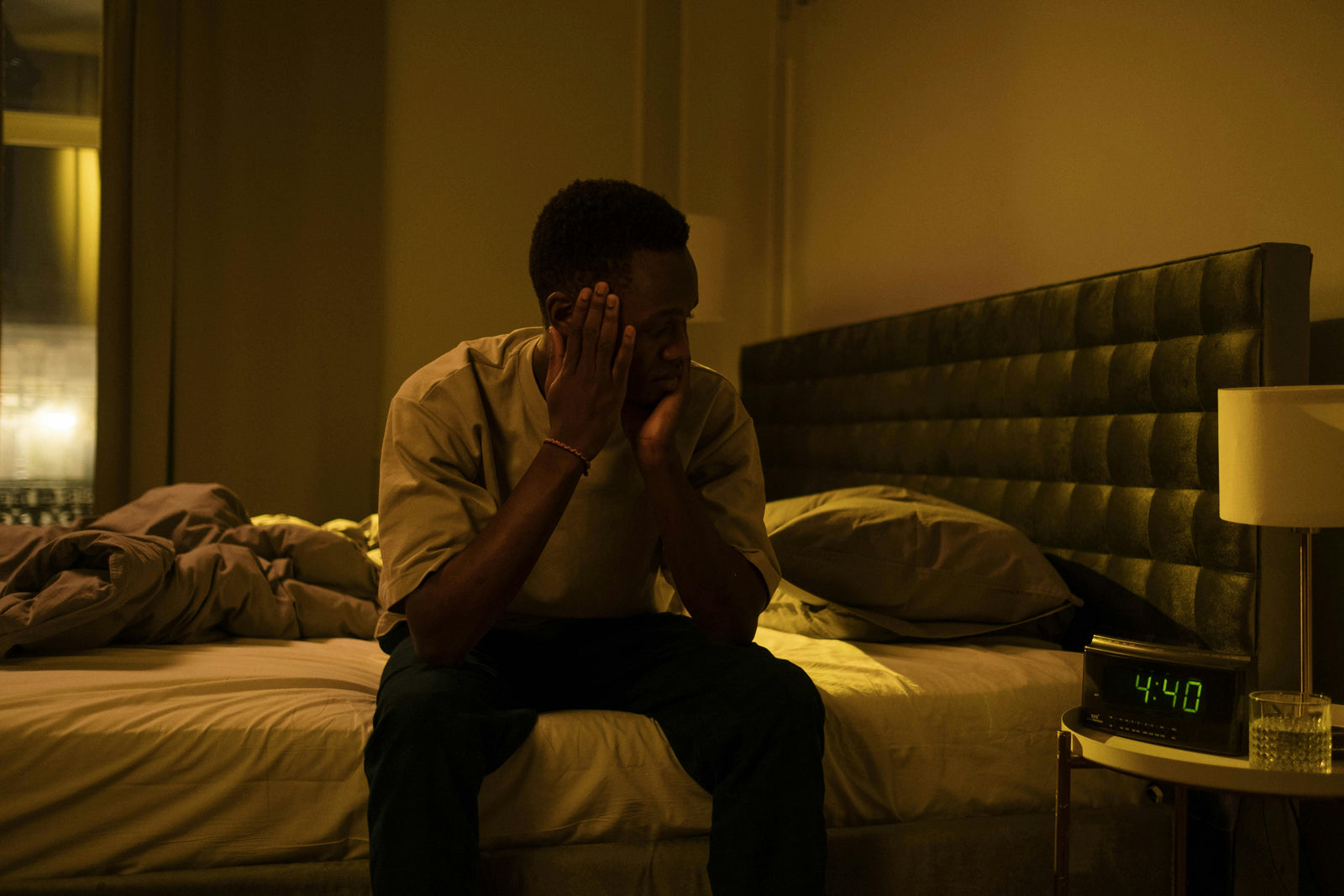 Man in bed with insomnia looks warily at his clock that says 4:40am