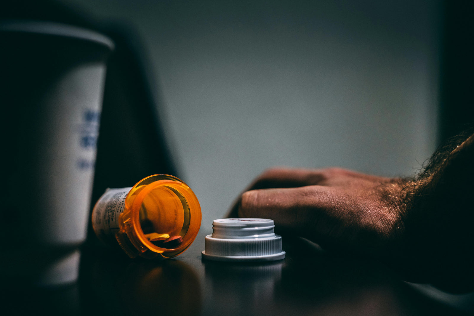 person struggling with addiction with an open pill bottle on the table